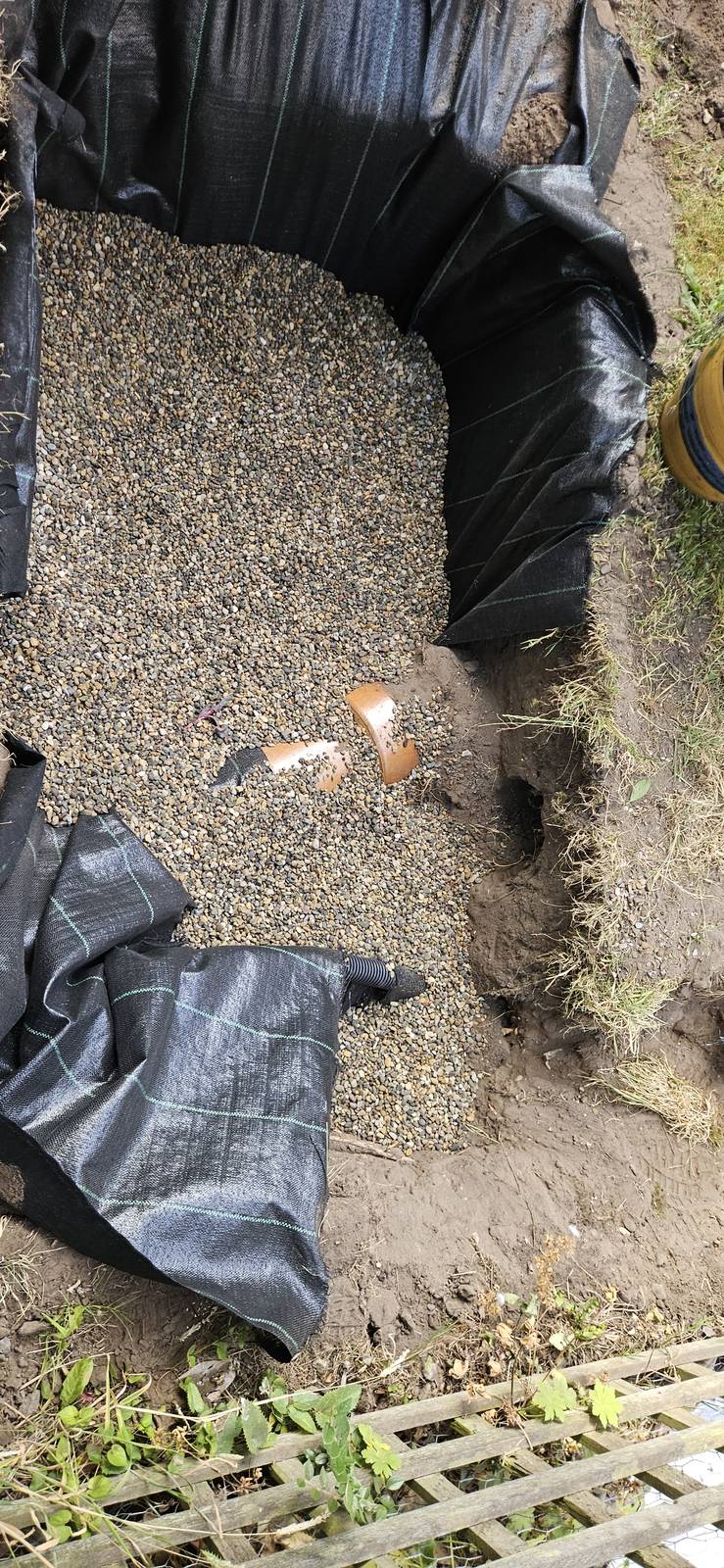 Soakaway pit lined with membrane and a shingle drainage bed